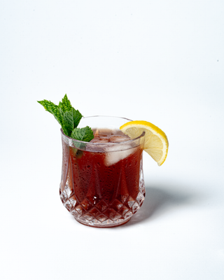 Punchy Pomegrante refreshing mocktail in a glass with mint sprig and lemon wedge